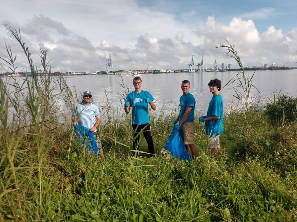 Four male honor volunteers cleaning up the marshes.